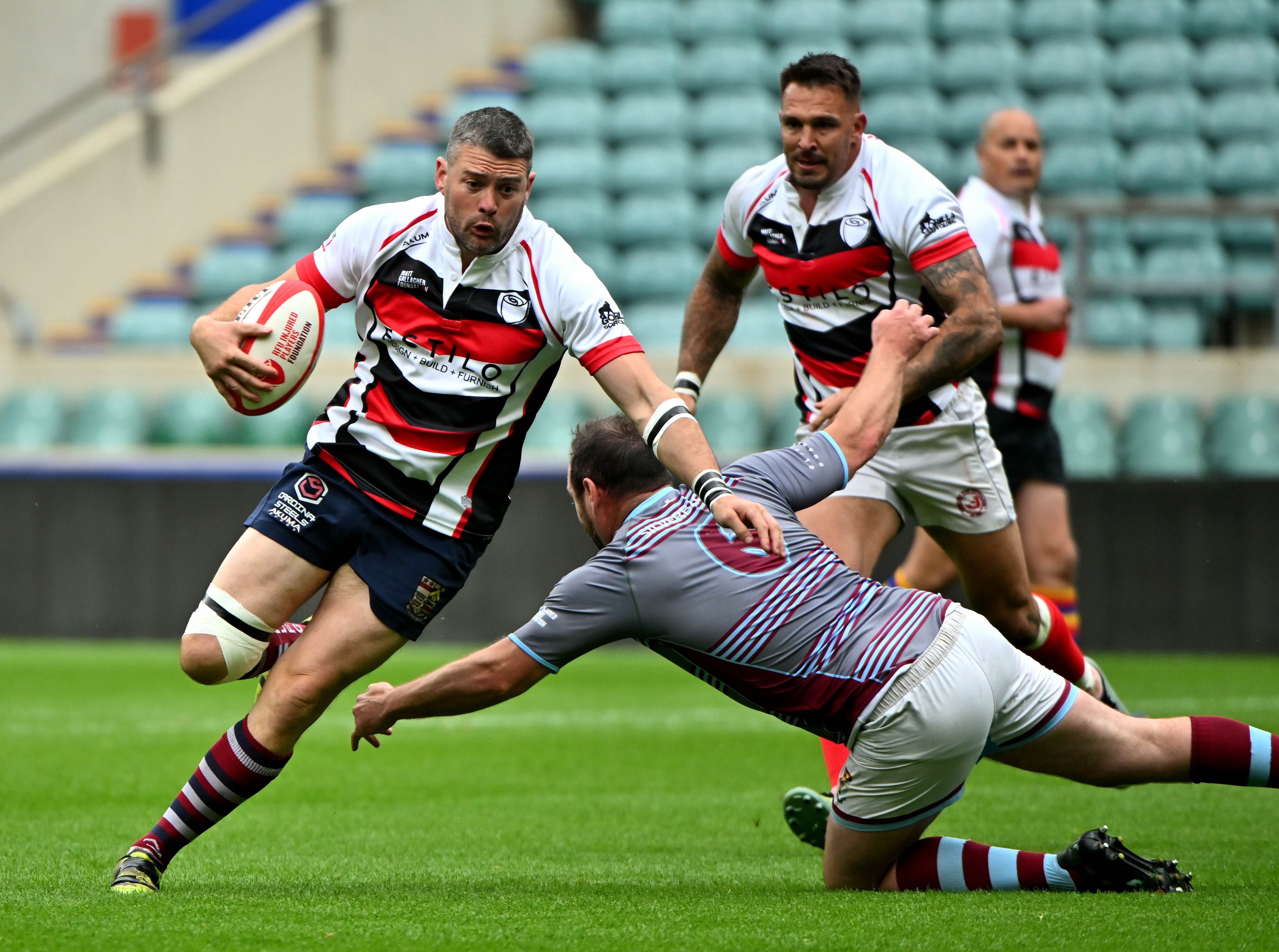 Image shows a male rugby player side stepping a tackler.