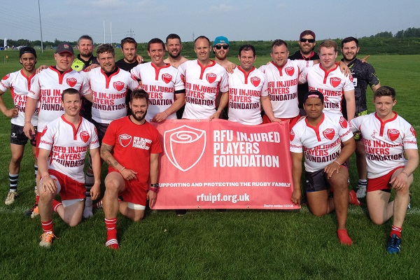 A rugby team holding an RFU Injured Players Foundation banner